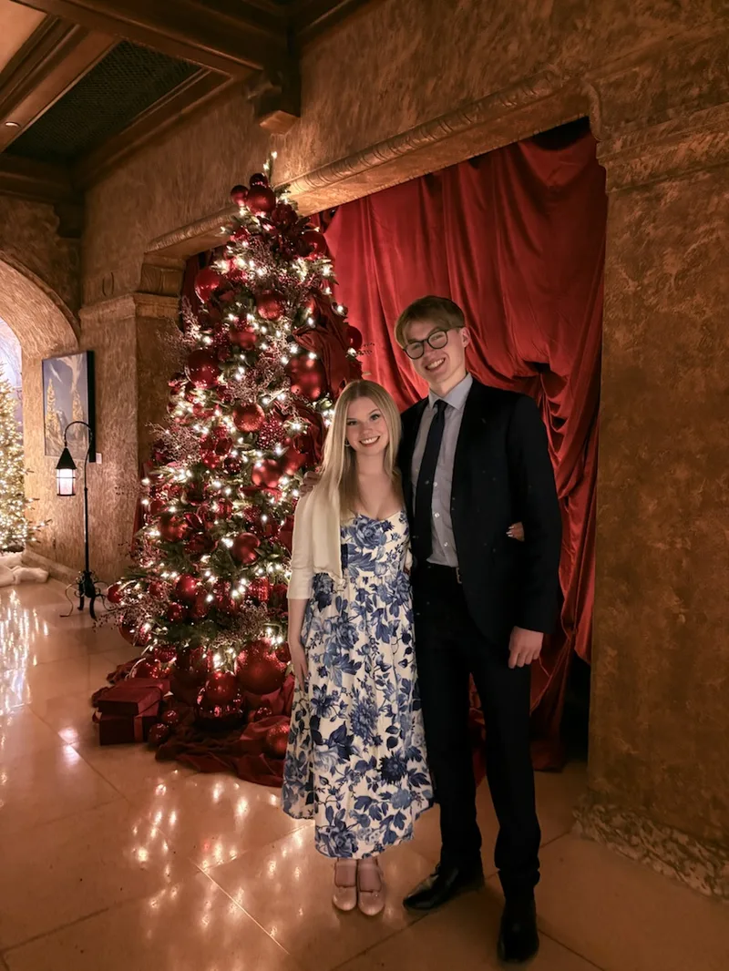 Matthew and Kelsey dressed up by a Christmas tree